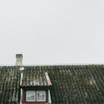 A vintage roof with a small window and chimney in Poland, showcasing old architectural charm.