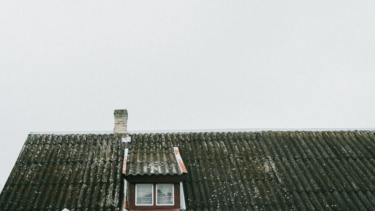 A vintage roof with a small window and chimney in Poland, showcasing old architectural charm.